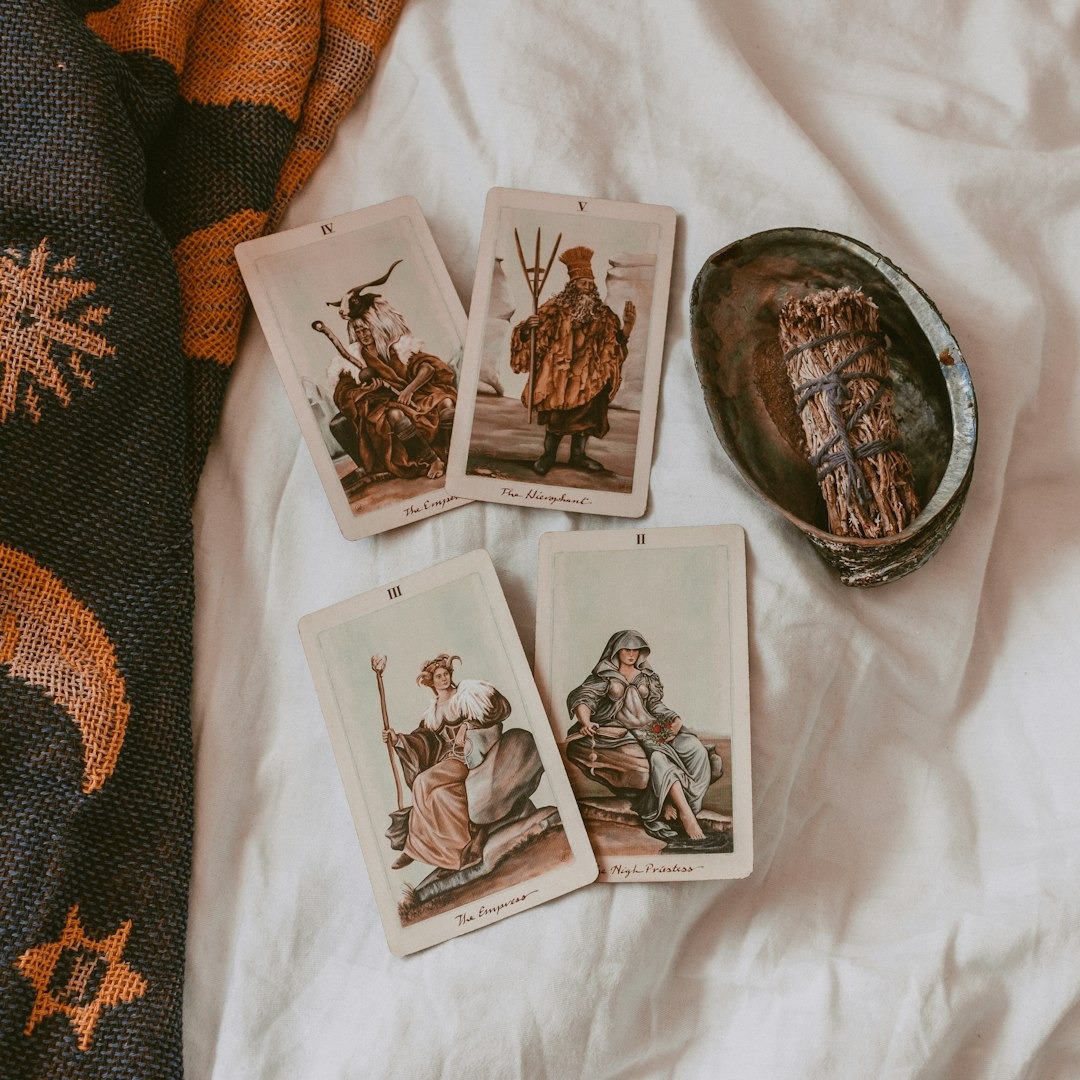 Tarot cards and smudging stick on rumpled white sheet.